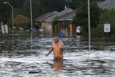 A man wades through a flooded street in Ascension Parish, Louisiana, U.S., August 15, 2016.  REUTERS/Jonathan Bachman/File Photo