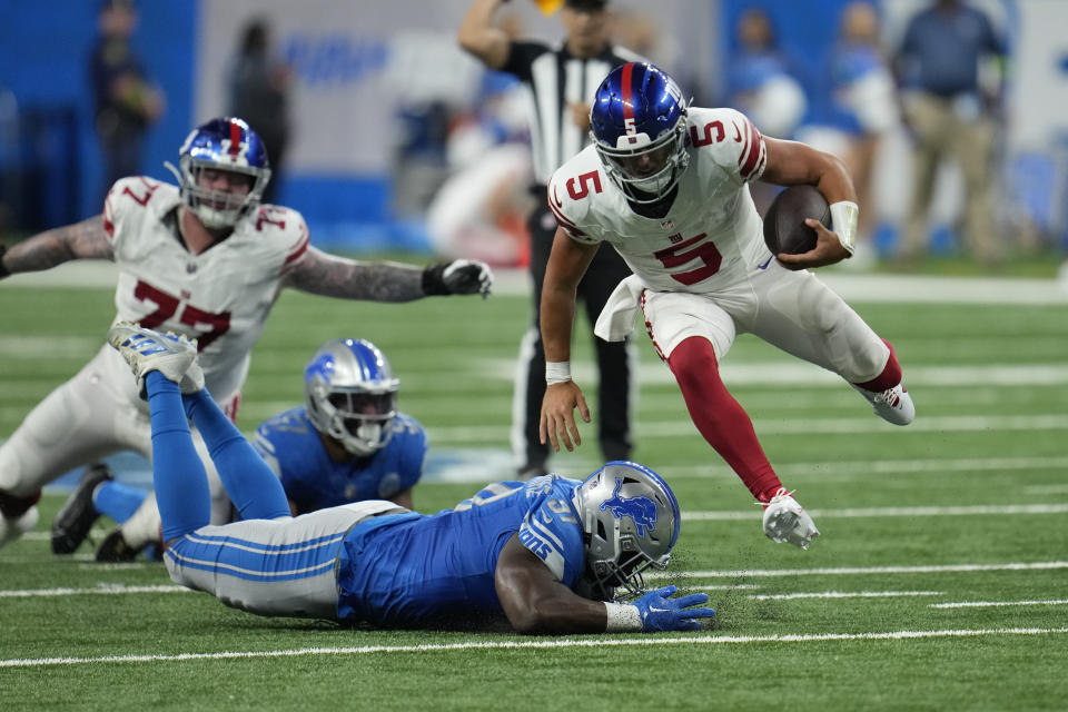 New York Giants quarterback Tommy DeVito (5) jumps over Detroit Lions defensive end Levi Onwuzurike during the second half of an NFL preseason football game, Friday, Aug. 11, 2023, in Detroit. (AP Photo/Paul Sancya)