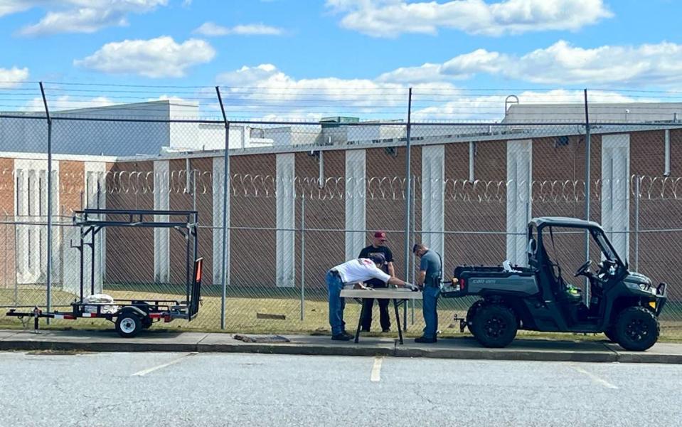 Workers fix a fence at the Bibb County jail in downtown Macon Monday afternoon after four inmates used a hole in the fence to escape early Monday morning. Jason Vorhees