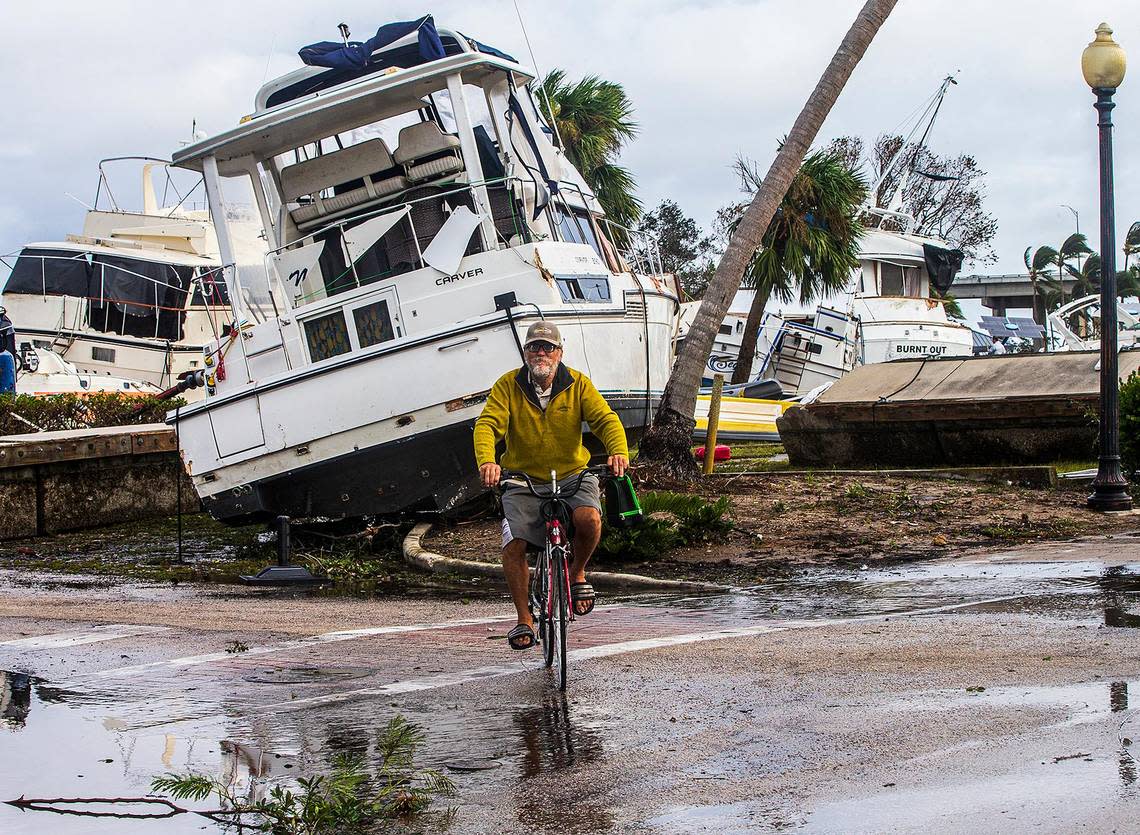 On Thursday, Sept. 29, 2022, a biker rides by boats that were run aground in the Legacy Harbour Marina in Fort Myers. Hurricane Ian hit the west coast of Florida as a Category 4 storm a day earlier. 