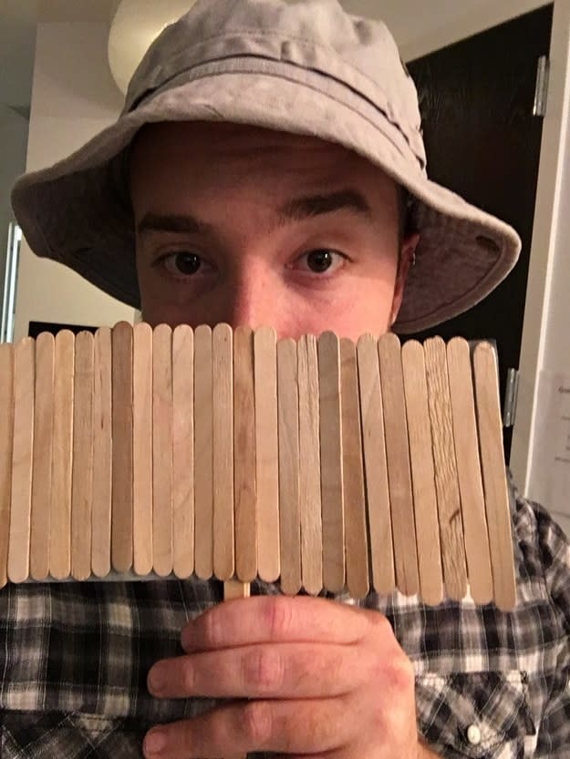 guy holding popsicle sticks in front of his face