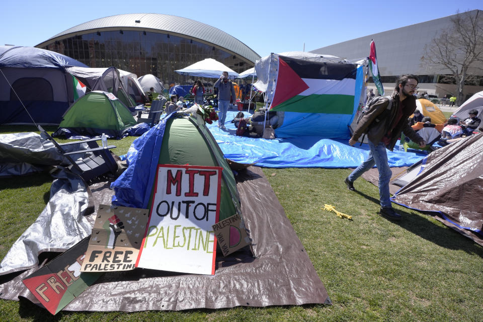 FILE - A passer-by, right, walks through an encampment of tents, Thursday, April 25, 2024, on the Massachusetts Institute of Technology campus, in Cambridge, Mass. (AP Photo/Steven Senne, File)