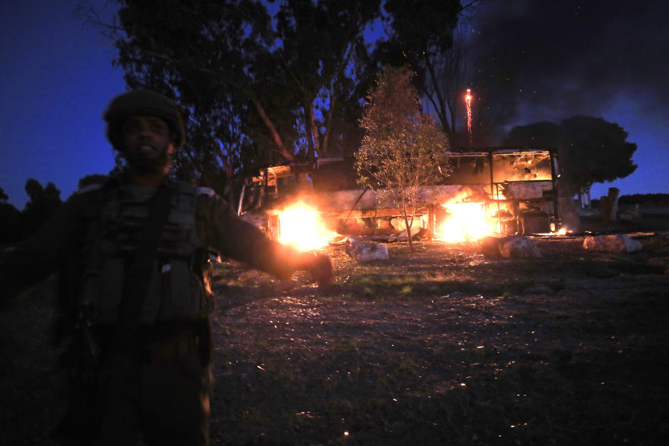 Un soldado israelí de pie junto a un autobús en llamas luego de que fue impactado por un proyectil lanzado desde la Franja de Gaza, el lunes 12 de noviembre de 2018. (AP Foto/Tsafrir Abayov)