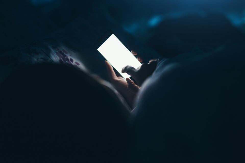 Woman texting and reading on smartphone in bed in midnight. Source: Getty Images