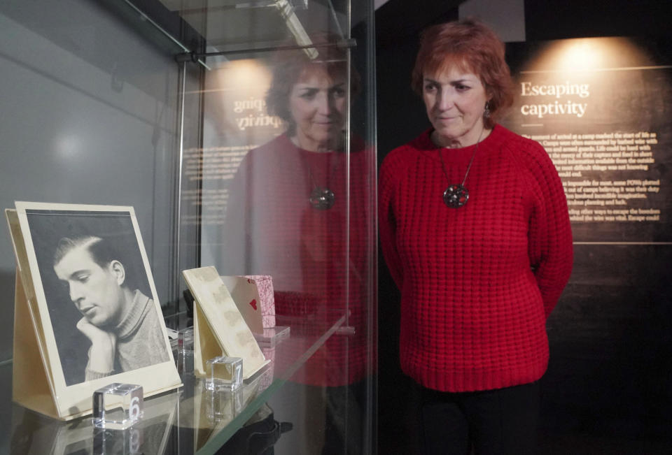 A member of National Archives staff looks at artefacts including coded writing concealed within a postcard and prototype playing cards containing secret maps used by MI9, a highly secret British government agency established in 1939 to help military personnel evade and escape capture on display as part of the Great Escapes: Remarkable Second World War Captives exhibition at the National Archives, in Kew, Richmond, England, Tuesday, Jan. 30, 2024. A new exhibit that opened Friday Feb. 2, 2024 at The National Archives in London uses the 80th anniversary of the so-called Great Escape by allied airmen from a German prisoner of war camp to explore escapes by captives of all kinds during World War II. (Jonathan Brady/PA via AP)