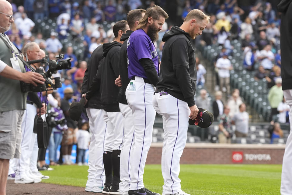 Colorado Rockies outfielders Hunter Goodman, right, and Charlie Blackmon join with teammates to stand during a moment of silence for the death of Willie Mays before a baseball game against the Los Angeles Dodgers Wednesday, June 19, 2024, in Denver. (AP Photo/David Zalubowski)