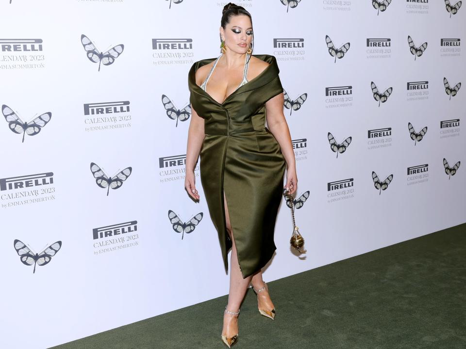 Ashley Graham in dark green dress in front of white background