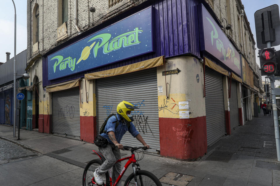 Un ciclista pasa el jueves 1 de abril de 2021 junto a una tienda cerrada durante una cuarentena para contener la propagación de la pandemia de COVID-19, en Santiago, Chile. (AP Foto/Esteban Félix)