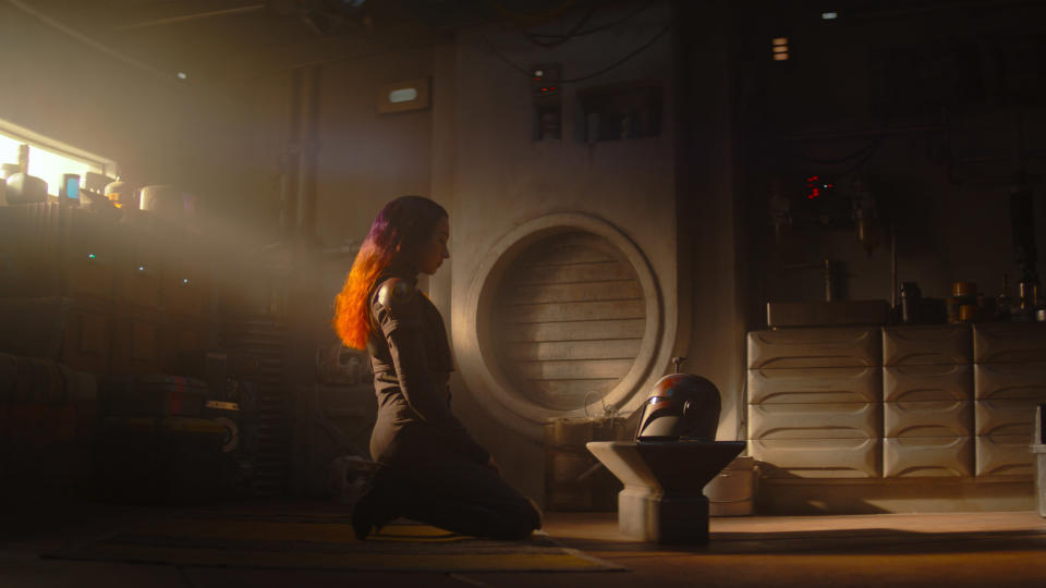 SAbine Wren (Natasha Liu Bordizzo) kneeling in front of a Mandalorian helm in Ahsoka.