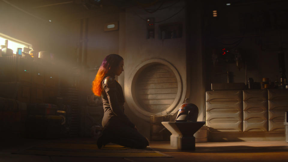 Sabine Wren (Natasha Liu Bordizzo) kneeling in front of a Mandalorian helm in Ahsoka.