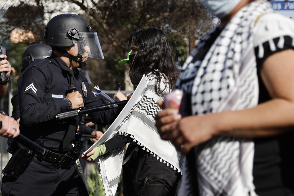 A law enforcement officer hits a protester while they face off on a street close to the Dolby Theatre as they demonstrate in support of Palestinians calling for a ceasefire in Gaza as the 96th Academy Awards Oscars ceremony is held nearby on Sunday, March 10, 2024, in the Hollywood section of Los Angeles. (AP Photo/Etienne Laurent)