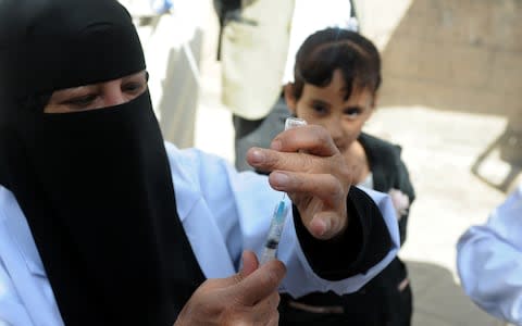 A girl looks at a nurse as she prepares an anti-diphtheria vaccine for her at a health centre in Sana'a, Yemen  - Credit: Mohammed Hamoud/Getty