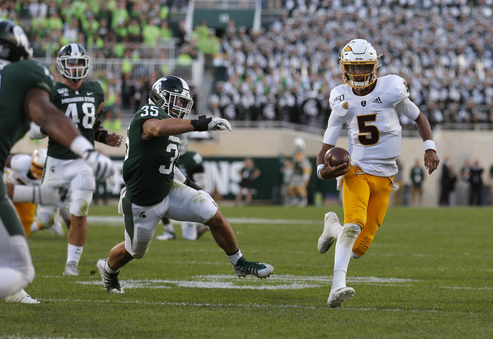 Arizona State quarterback Jayden Daniels, right, scrambles for a first down against Michigan State's Joe Bachie (35) and Kenny Willekes (48) late in the fourth quarter of an NCAA college football game, Saturday, Sept. 14, 2019, in East Lansing, Mich. (AP Photo/Al Goldis)