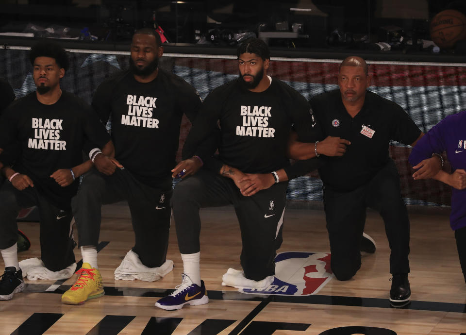 Los Angeles Lakers' LeBron James wears a Black Lives Matter shirt and kneels with teammates on the court.