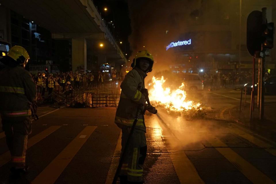 A firefighter sprays water towards the burning barricade during a rally outside Mong Kok Police Station. (REUTERS)