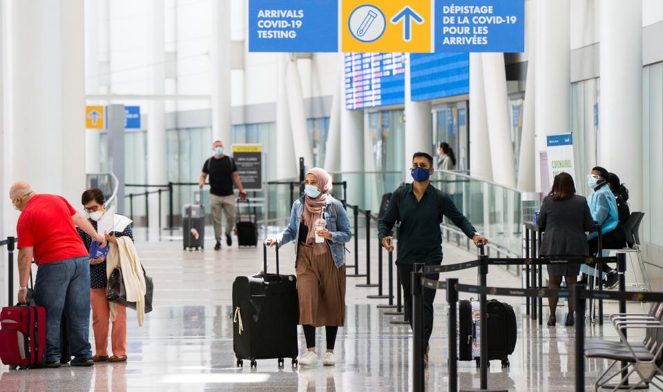 Travelers wearing face masks walk out of the arrivals hall at Toronto Pearson International Airport in Mississauga, Ontario, Canada, on July 5, 2021. Starting from Monday, "fully vaccinated" Canadians and permanent residents can enter Canada without undergoing quarantine. (Photo by Zou Zheng/Xinhua via Getty Images)