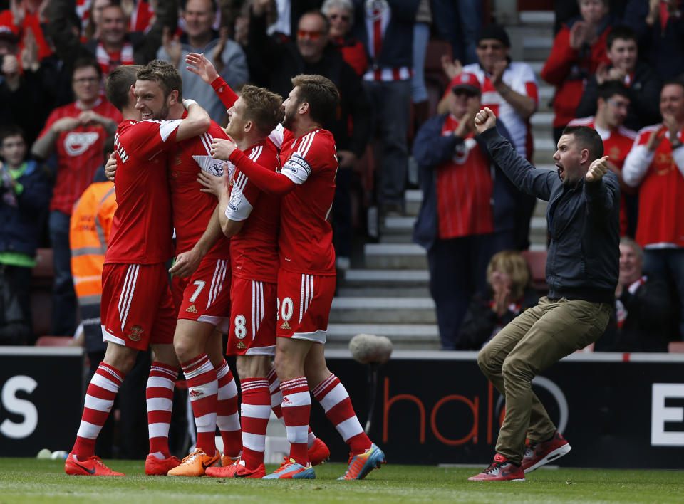 Southampton's Rickie Lambert, second left, celebrates his goal against Manchester United with teammates as a supporter, right, runs onto the pitch to join them during their English Premier League soccer match at St Mary's stadium, Southampton, England, Sunday, May 11, 2014. (AP Photo/Sang Tan)