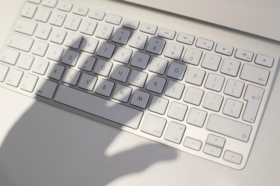 A shadow of a hand over a computer keyboard. (Getty Images/Science Photo Library)