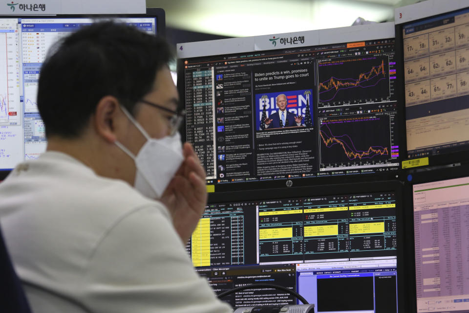 A screen shows Democratic presidential candidate former Vice President Joe Biden during a news program about the U.S. elections as a currency trader works at the foreign exchange dealing room of the KEB Hana Bank headquarters in Seoul, South Korea, Friday, Nov. 6, 2020. (AP Photo/Ahn Young-joon)