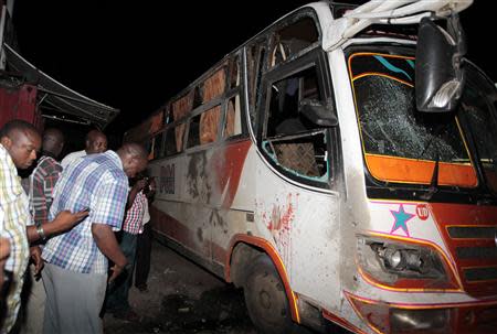 Plain-clothed policemen check the damage on a passenger bus at the scene of an explosion at the populous Mwembe Tayari market, in the Kenyan coastal town of Mombasa May 3, 2014. REUTERS/Joseph Okanga