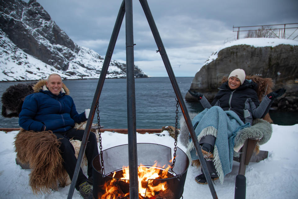 Monica Galetti and Rob Rinder warming up by the firepit at Nusfjord Arctic Resort, Norway.