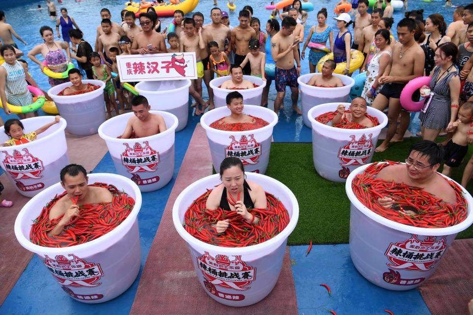 <p>Teilnehmer der „Spicy Barrel Challenge“ im chinesischen Chongqing nehmen ein Bad in mit Chilischoten gefüllten Fässern. (Bild: CNS via REUTERS/Chen Chao) </p>