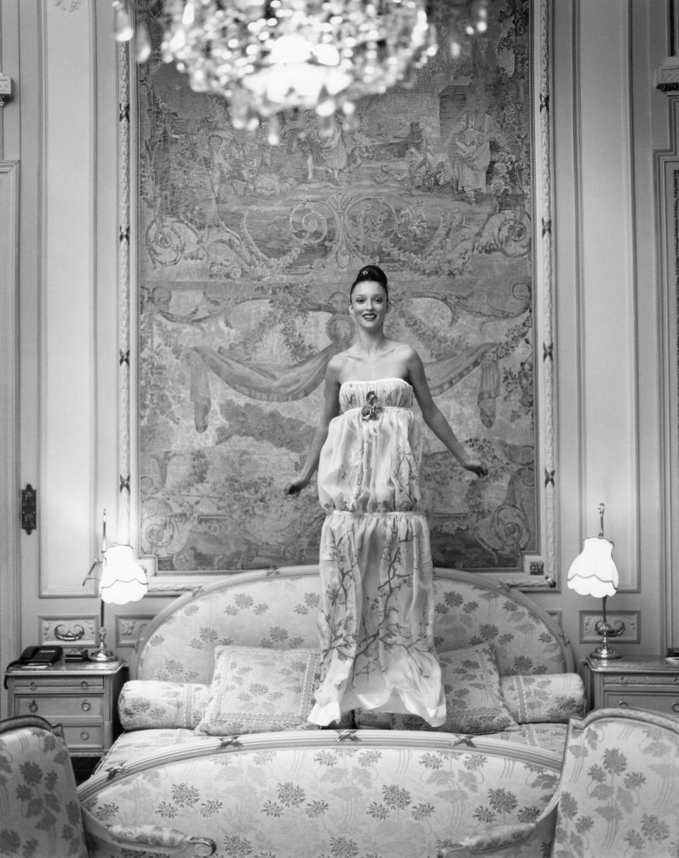 Model Audrey Marnay wearing a dévoré chiffon flower-print strapless dress by Emmanuel Ungaro Haute Couture, jumping on a bed in the Suite Duc de Windsor at the Hôtel Ritz, Paris; dress fabric by Etro