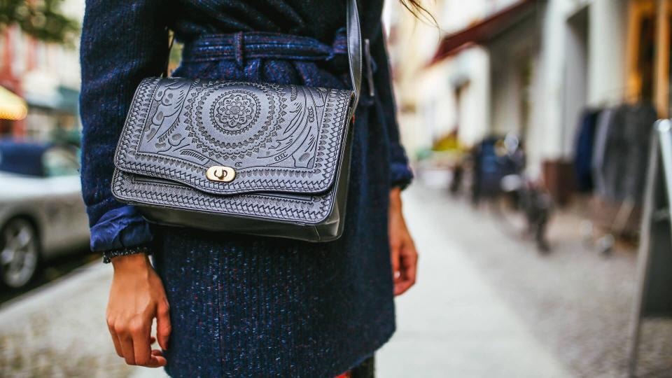 Close up on the young woman's purse and a dark coat on the streets of Berlin, in Kreuzberg - Schoneberg district.