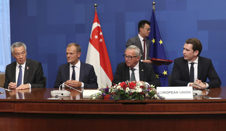 Singapore's Lee Hsien Loong, left, signs an agreement of understanding during an EU-ASEM summit in Brussels, Friday, Oct. 19, 2018. The European Union and Singapore on Friday signed three agreements, taking their political, trade, and investment relations to a new level. From right, Austrian Chancellor Sebastian Kurz, European Commission President Jean-Claude Juncker and European Council President Donald Tusk. (AP Photo/Francisco Seco, Pool)