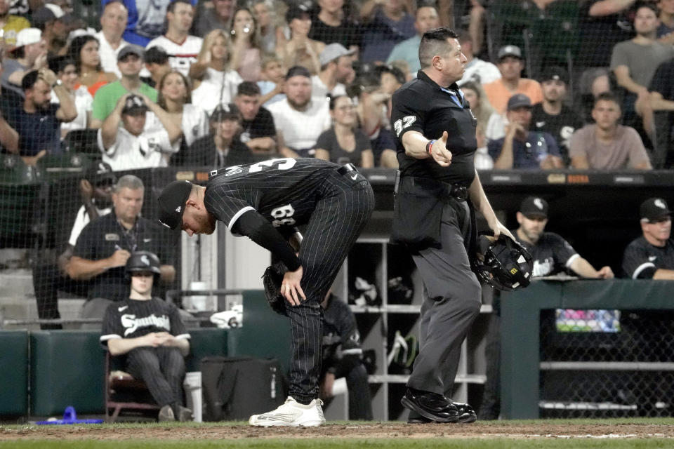 Chicago White Sox relief pitcher Aaron Bummer bends over at home as home plate umpire Carlos Torres signals two runs scored off Bummer's throwing error to catcher Yasmani Grandal during the sixth inning of a baseball game against the Milwaukee Brewers Friday, Aug. 11, 2023, in Chicago. (AP Photo/Charles Rex Arbogast)