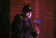 A nearby resident shoots video of a deadly shooting scene involving Phoenix Police officers in Phoenix, Ariz., Sunday, March 29, 2020. At least three Phoenix police officers were shot Sunday night on the city's north side, authorities said. (AP Photo/Ross D. Franklin)