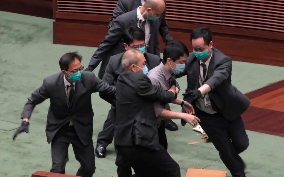 Pro-democracy lawmaker Ted Hui, center, struggles with security personnel during a debate on a bill that would criminalize insulting or abusing the Chinese anthem in Hong Kong - AP