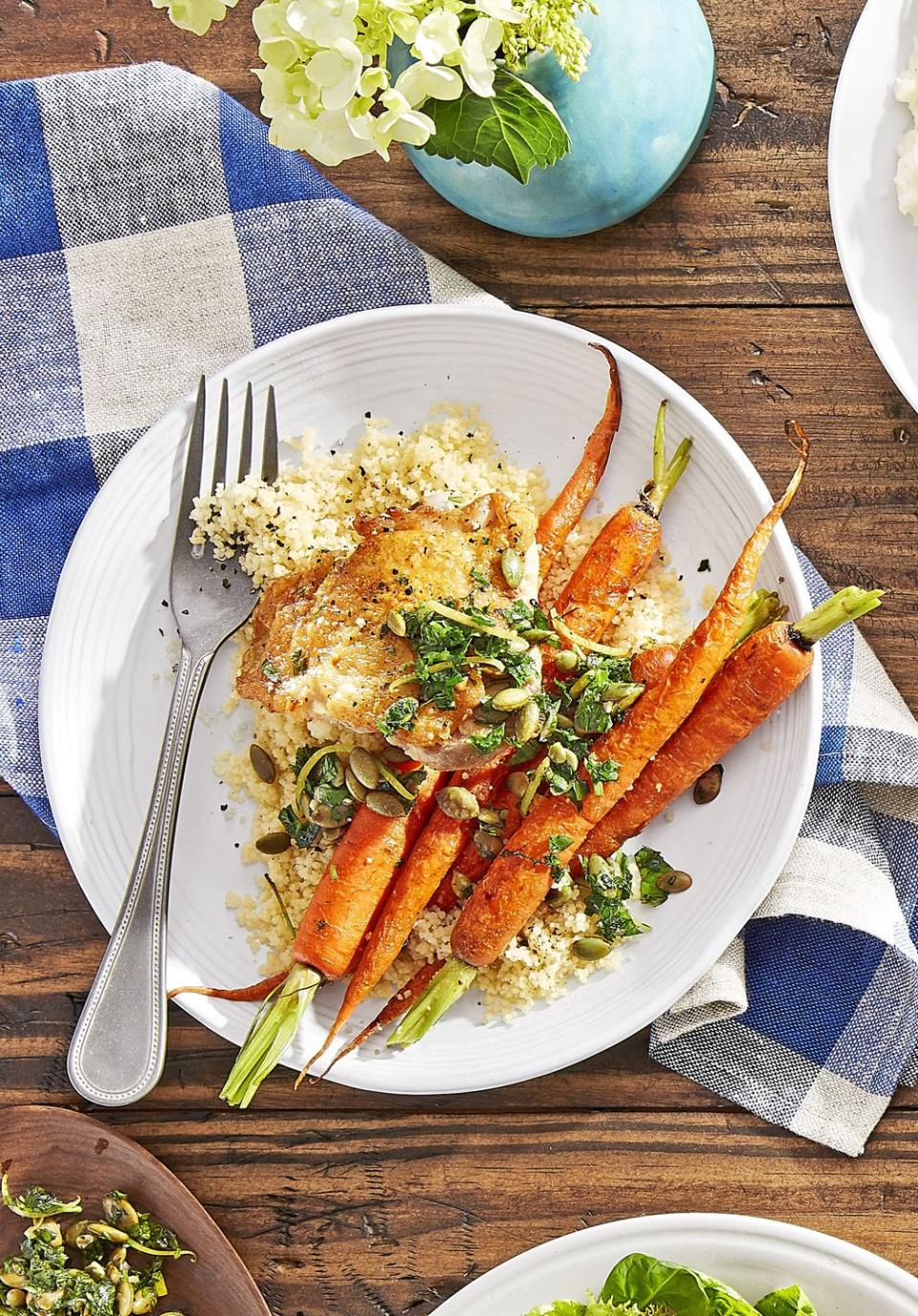 crispy chicken with roasted carrots and couscous on a a white plate with a fork