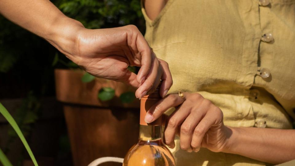 Close-up of a person opening a bottle of rose wine