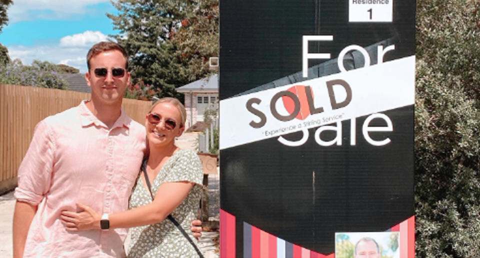 Victorian couple Harry Baker and Kate Osmond standing next to sold sign at Melbourne property. 