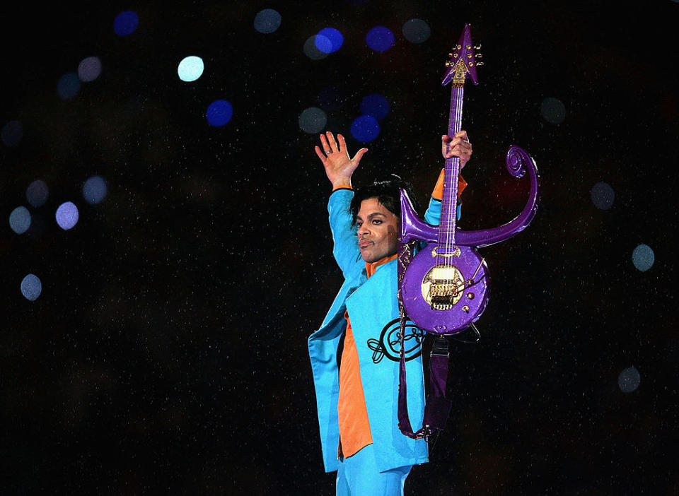 Prince holding up his purple guitar onstage