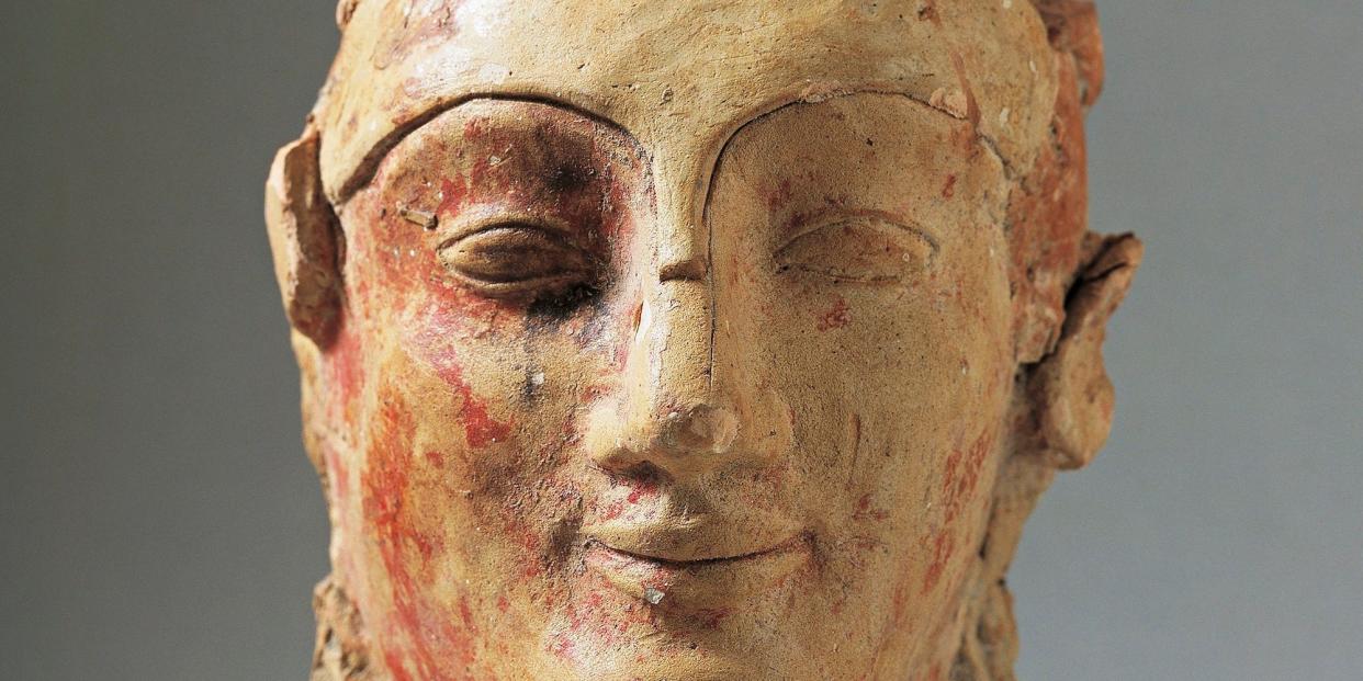 A smiling helmeted head of Athena from the 5th century BC, terracotta sculpture from the Temple of Zeus in Agrigento, Sicily, Italy. Traces of red paint can be seen and much of the helmet itself is missing.