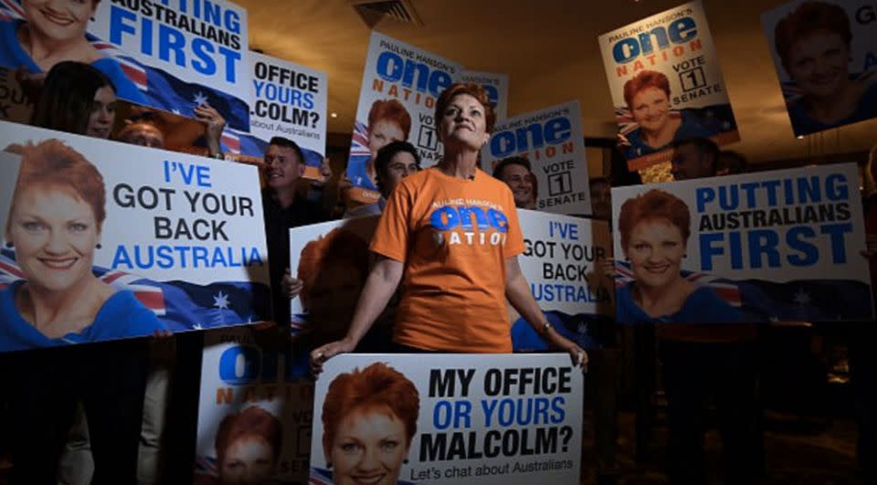 Pauline Hanson stands before a placard that reads 