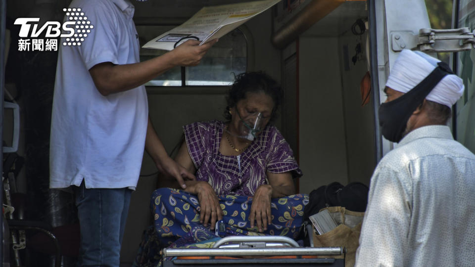 圖／一位72歲的婦女因為染疫造成呼吸困難，坐在救護車上接受供氧輔助，達志影像美聯社