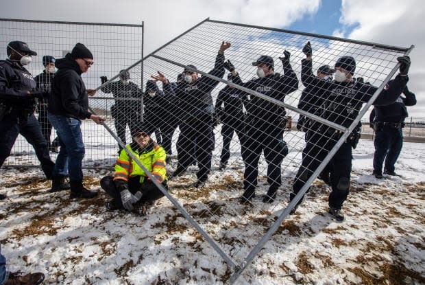 Supporters try to tear down the fence as police struggle with them outside GraceLife Church near Edmonton on Sunday. The church has been fenced off by police and Alberta Health Services in an effort to enforce COVID-19 restrictions.  (Jason Franson/The Canadian Press - image credit)