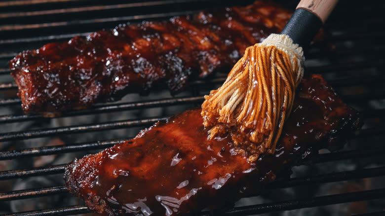 brushing barbecue sauce on ribs