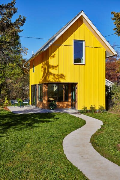 The accessory dwelling unit behind the home of Sonja Batalden in Saint Paul, Minnesota, has cheery yellow siding that the entrance appears to carve into. 