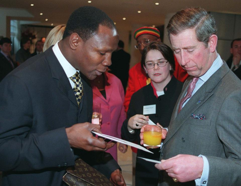 El entonces príncipe Carlos disfrutando de un jugo de naranja junto al boxeador Chris Eubank en una gala sobre el cáncer de mama en 1998. (PA)