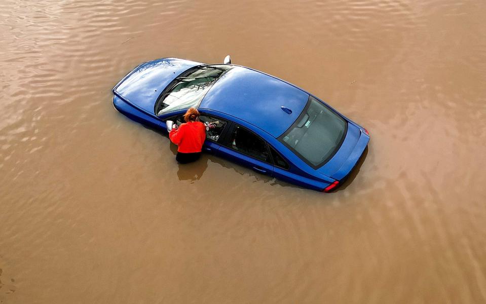 A woman checks on a flooded car in Worcester city centre