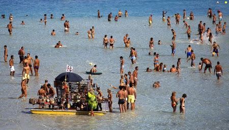 People sunbathe on the beach in the Italian town of Stintino, northwest of Sardinia, in this file photo taken August 9, 2010. REUTERS/Alessandro Bianchi/Files