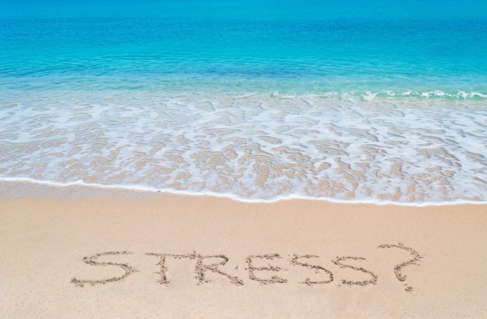 palabra estrés escrita en la arena de la playa, junto al mar