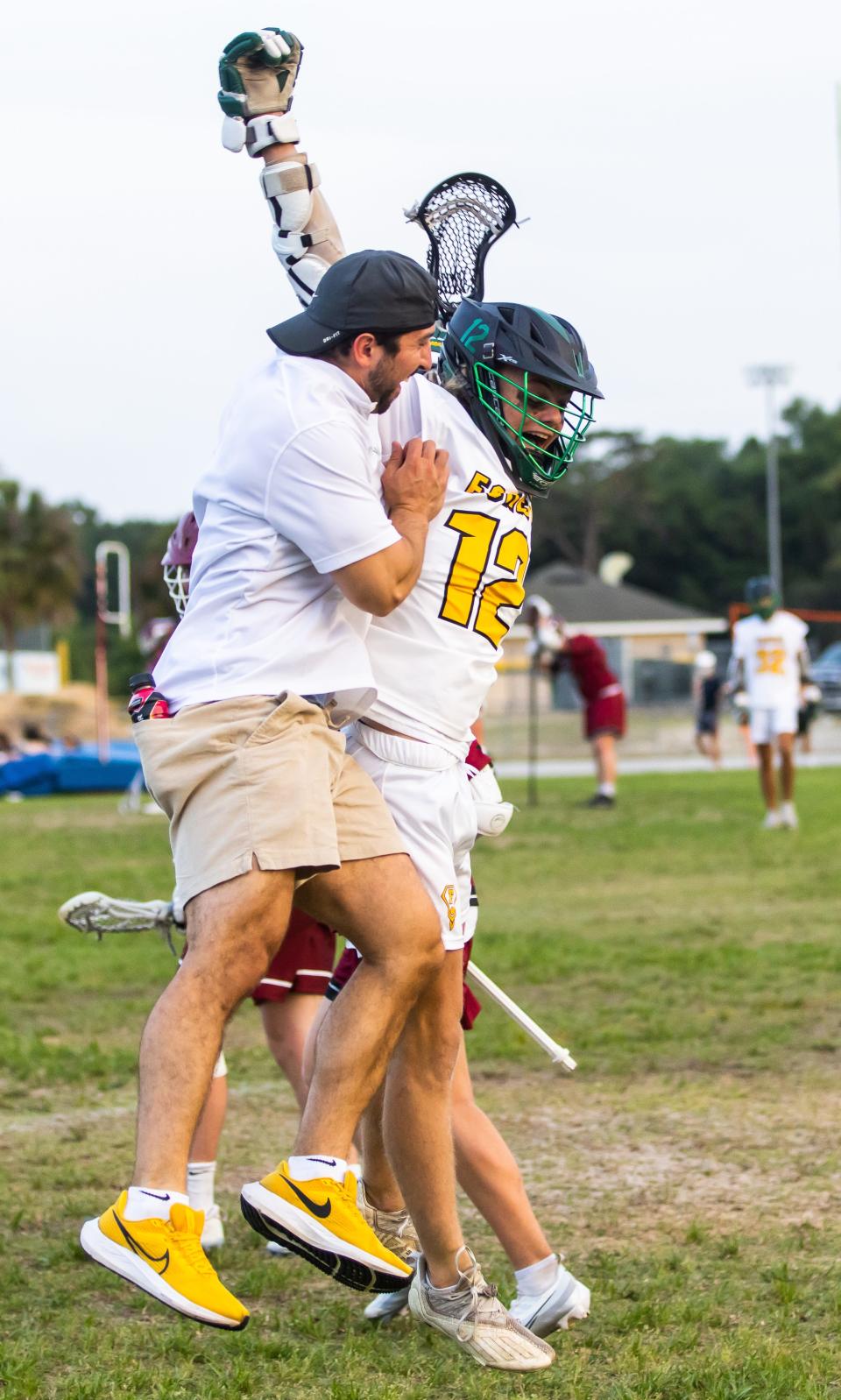 Forest Wildcats Alexander Holland (12) celebrates his goal with Assistant Coach Frank Ranfone, left. The Forest High School Wildcats hosted the Chiles Timberwolves at Forest High School in Ocala, FL on Wednesday, April 5, 2023. Forest led at the half 9-2. [Doug Engle/Ocala Star Banner]