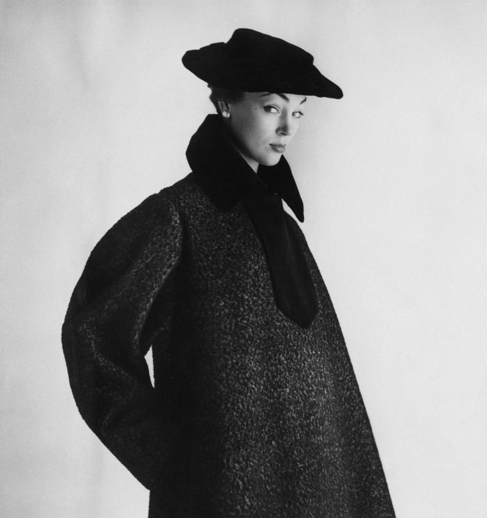 <p>A women modeling a velvet-trimmed gray coat with a cap-effect silhouette. </p>