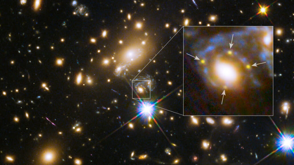  An image of a distant galaxy cluster, with a zoomed-in box showing 4 yellow dots around a large foreground galaxy. These dots are 4 separate images of the same supernova. 