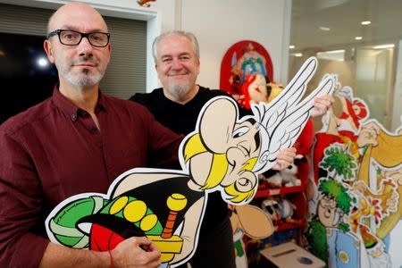 Author Jean-Yves Ferri (L) and illustrator Didier Conrad (R) pose holding a cardboard cut-out of Asterix during an interview for their new comic album "Asterix et la Transitalique" (Asterix and the Chariot Race) in Vanves near Paris, France, October 17, 2017, the latest in the series created by illustrator Albert Uderzo and writer Rene Goscinny in 1959. Picture taken October 17, 2017. REUTERS/Philippe Wojazer